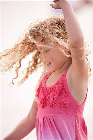 simsearch:6128-08747842,k - Young girl with curly blonde hair twirls around as she dances while posing for a portrait. Stockbilder - Premium RF Lizenzfrei, Bildnummer: 6128-08747806