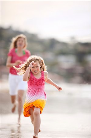 simsearch:6128-08747866,k - Young girl makes a serious face as she runs away from her mother as they play on a beach. Foto de stock - Sin royalties Premium, Código: 6128-08747808