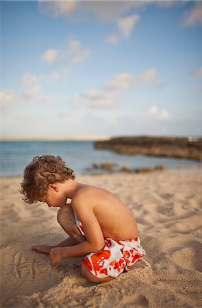 ponerse en cuclillas - Young boy drawing a tic tac toe grid in the sand on a beach. Foto de stock - Sin royalties Premium, Código: 6128-08747948