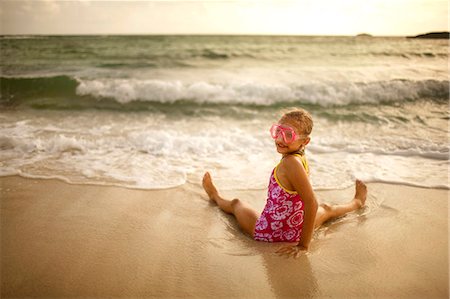 swimmer (female) - Portrait of a smiling young girl wearing swimming goggles while sitting in shallow water at the beach. Stock Photo - Premium Royalty-Free, Code: 6128-08747936