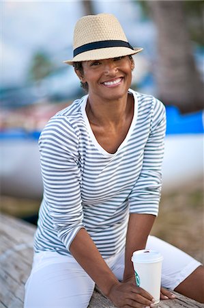 Portrait of mature woman happily sitting on log with coffee. Stock Photo - Premium Royalty-Free, Code: 6128-08748042