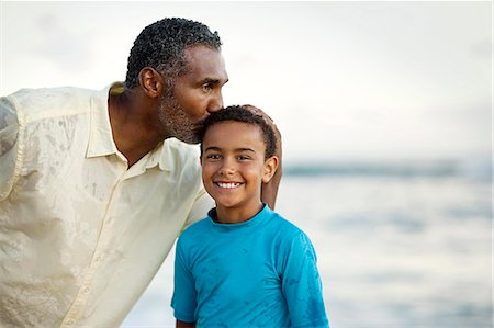 Happy boy at the beach being kissed on the head by his grandfather. Stock Photo - Premium Royalty-Free, Code: 6128-08748091