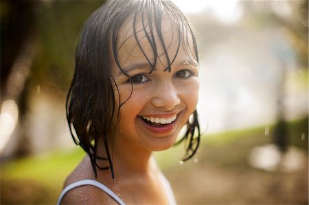 play - Portrait of a smiling young girl soaked from playing in the garden in the rain. Stock Photo - Premium Royalty-Free, Code: 6128-08748026