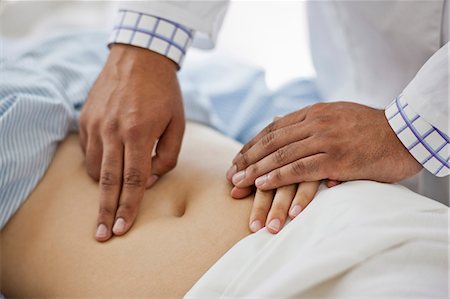 Doctor's hands examining a female patient's abdomen. Stock Photo - Premium Royalty-Free, Code: 6128-08748161