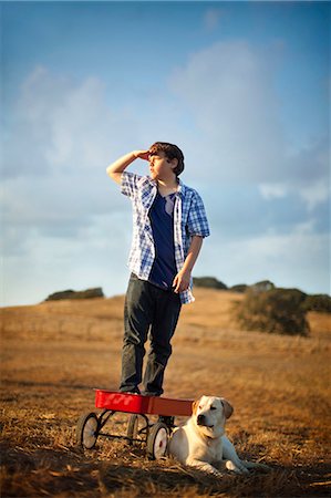 simsearch:6128-08747680,k - Boy standing on red wagon with his dog in the middle of the field. Foto de stock - Sin royalties Premium, Código: 6128-08748185