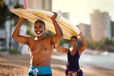 simsearch:6128-08748022,k - Mid adult couple carrying a surfboard on a beach. Stock Photo - Premium Royalty-Free, Code: 6128-08748114