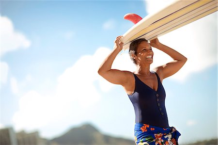 simsearch:6128-08798792,k - Mid adult woman carrying a surfboard on a beach. Fotografie stock - Premium Royalty-Free, Codice: 6128-08748115