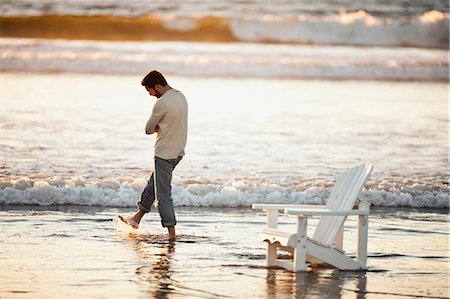 simsearch:600-02346208,k - Man with his arms crossed looks down despondently as he wades in the sea as the sun sets. Stockbilder - Premium RF Lizenzfrei, Bildnummer: 6128-08766660