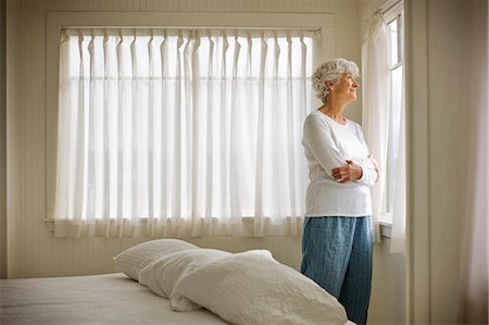 simsearch:649-09123654,k - Elderly woman looking through bedroom window. Photographie de stock - Premium Libres de Droits, Code: 6128-08766694