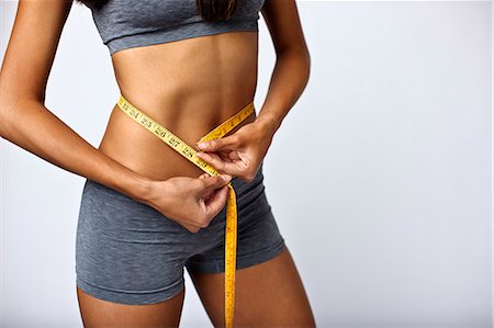 Close up of young kickboxer measuring her toned stomach. Stock Photo - Premium Royalty-Free, Code: 6128-08766875