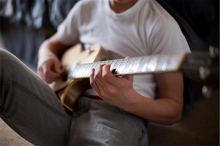 Boy sitting on bed playing guitar. Stock Photo - Premium Royalty-Free, Code: 6128-08766878