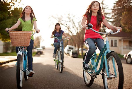 simsearch:6102-07843140,k - Group of teenage girls cycling along the street together. Photographie de stock - Premium Libres de Droits, Code: 6128-08766806