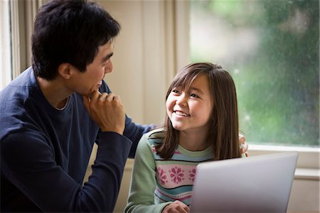 study online at home - Father and daughter smile while working on a laptop together. Stock Photo - Premium Royalty-Free, Code: 6128-08766944