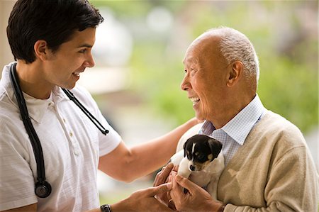 simsearch:6128-08738056,k - Male nurse laughs and talks with a senior man holding a puppy. Foto de stock - Sin royalties Premium, Código: 6128-08766949