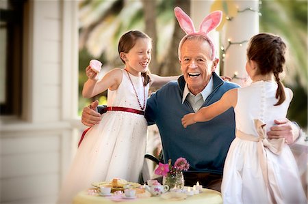 Grandfather hugging granddaughters at tea party. Stock Photo - Premium Royalty-Free, Code: 6128-08766923