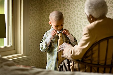 simsearch:6128-08738117,k - Grandmother sits in a chair and watches her grandson tying a necktie. Foto de stock - Sin royalties Premium, Código: 6128-08766930