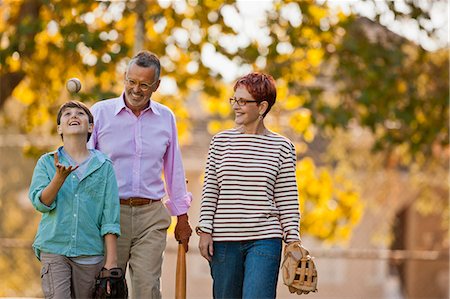 Smiling family walking to a park to play baseball. Stock Photo - Premium Royalty-Free, Code: 6128-08767152