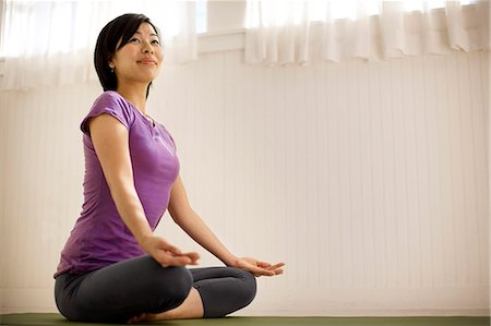 simsearch:6128-08738452,k - Young woman meditating while sitting on a yoga mat inside her home. Foto de stock - Sin royalties Premium, Código: 6128-08767167