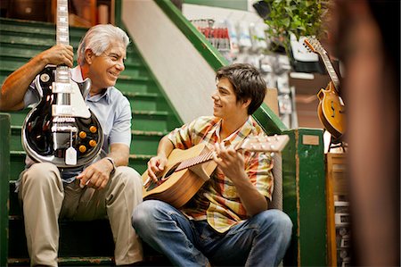 Smiling senior man playing guitar with his teenage grandson. Foto de stock - Sin royalties Premium, Código: 6128-08767272