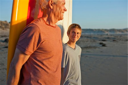 seniors surfing - Smiling senior man and grandson standing on a beach with surfboards. Photographie de stock - Premium Libres de Droits, Code: 6128-08767207