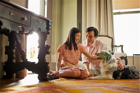 family stroke sit - Smiling father and daughter petting their dog. Stock Photo - Premium Royalty-Free, Code: 6128-08767204