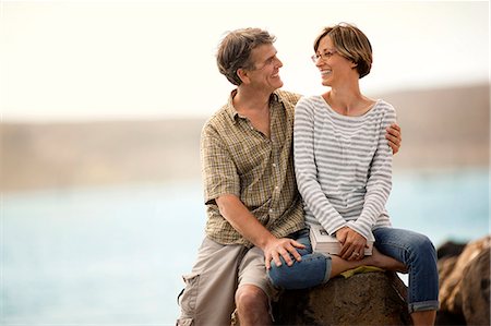 Smiling middle aged couple sitting together at a beach. Stock Photo - Premium Royalty-Free, Code: 6128-08767219