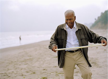 Senior man playing with a hula hoop at the beach. Stock Photo - Premium Royalty-Free, Code: 6128-08780366