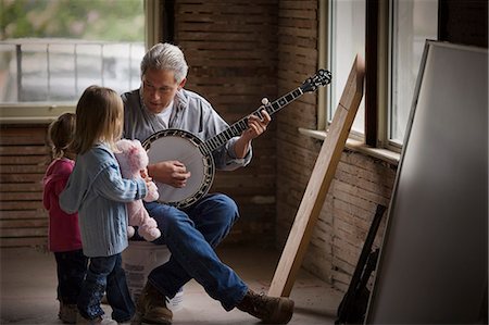 Mature man playing a banjo to his two young daughters. Foto de stock - Sin royalties Premium, Código: 6128-08780369