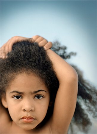 simsearch:6128-08798764,k - Portrait of a young girl with curly black hair standing with her arms above her head. Stock Photo - Premium Royalty-Free, Code: 6128-08780378