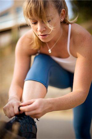 Active young woman tying the laces on her running shoe. Stock Photo - Premium Royalty-Free, Code: 6128-08780450