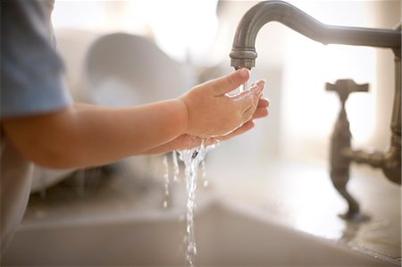 Toddler holding hands under tap Stock Photo - Premium Royalty-Free, Code: 6128-08780475