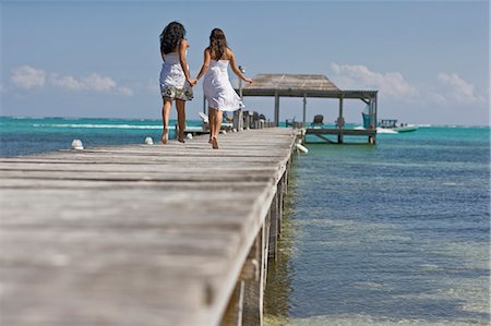 pals, spain - Two young adult girls running along a jetty by the beach. Fotografie stock - Premium Royalty-Free, Codice: 6128-08780415