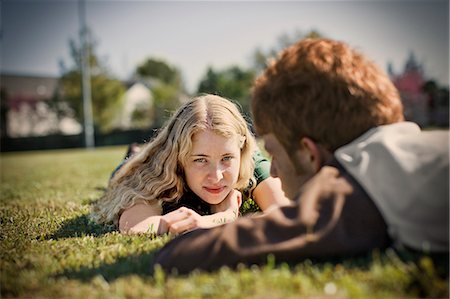 simsearch:400-05372366,k - Portrait of a teenage girl lying down on a grassy field with her boyfriend. Photographie de stock - Premium Libres de Droits, Code: 6128-08780529