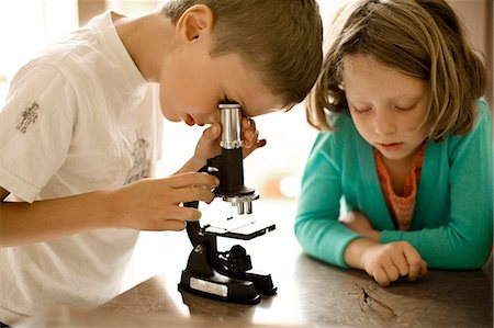 Brother and sister experimenting with a microscope. Foto de stock - Royalty Free Premium, Número: 6128-08780536