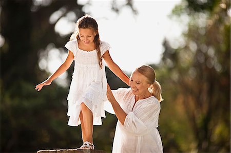 simsearch:6128-08780782,k - Grandmother helps her granddaughter balance across a brick fence. Foto de stock - Royalty Free Premium, Número: 6128-08780648