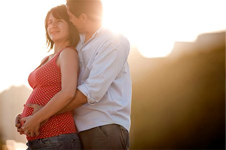 sonneneruption - Twenty-Something man hugs and kisses his pregnant wife. Stockbilder - Premium RF Lizenzfrei, Bildnummer: 6128-08780651
