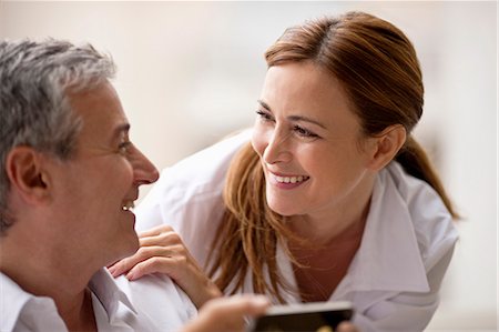 Professional couple looking at something on an iphone. Foto de stock - Sin royalties Premium, Código: 6128-08780685