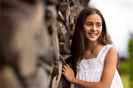 Portrait of young girl next to stack of firewood. Stock Photo - Premium Royalty-Free, Code: 6128-08780769