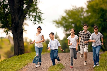 simsearch:6128-08767314,k - Small group of children running together over gravel road. Stock Photo - Premium Royalty-Free, Code: 6128-08780818