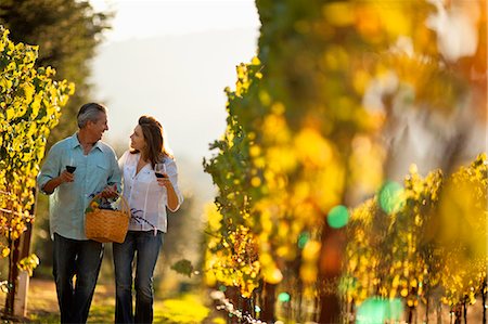 simsearch:6128-08738561,k - Mature couple enjoy romantic walk through vineyard while tasting wine. Stock Photo - Premium Royalty-Free, Code: 6128-08780944