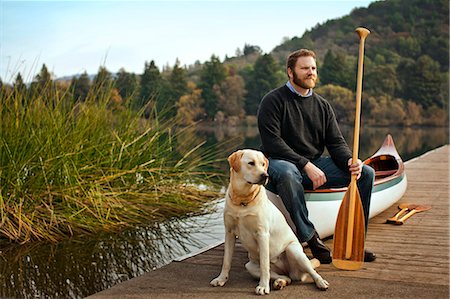 fall sports - Portrait of a canoeist sitting on a lake pier with his dog. Photographie de stock - Premium Libres de Droits, Code: 6128-08780999