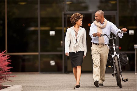 simsearch:693-03307851,k - Businesswoman walks with a man walking his bicycle. Photographie de stock - Premium Libres de Droits, Code: 6128-08780905