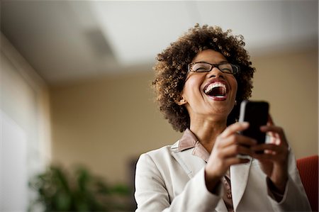 simsearch:6128-08728169,k - Businesswoman laughing as she looks at cell phone. Stock Photo - Premium Royalty-Free, Code: 6128-08780906