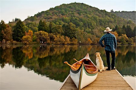 dog water - Canoeist standing on the edge of a lake pier with his dog. Stock Photo - Premium Royalty-Free, Code: 6128-08781004