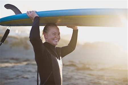 simsearch:6128-08747850,k - Young woman at the beach wearing a wetsuit and carrying a surfboard Photographie de stock - Premium Libres de Droits, Code: 6128-08798756