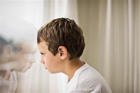 Boy looking out a window Stock Photo - Premium Royalty-Free, Code: 6128-08798764