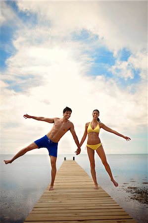 simsearch:6128-08798831,k - Young couple play on an ocean pier. Fotografie stock - Premium Royalty-Free, Codice: 6128-08798789
