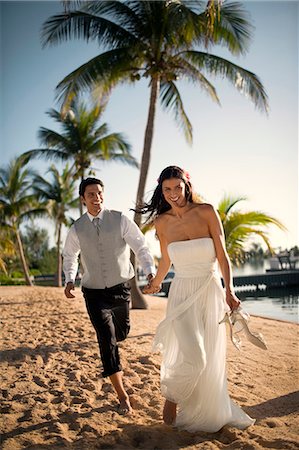 Playful young newlywed couple walking along a beach after their wedding. Stock Photo - Premium Royalty-Free, Code: 6128-08798853