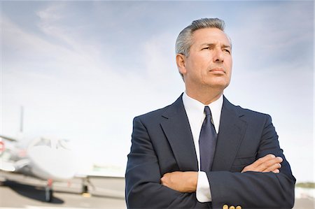 A businessman standing at the airport with his arms folded Stock Photo - Premium Royalty-Free, Code: 6128-08798898