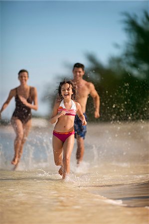Happy family running along a tropical beach in the shallows. Foto de stock - Sin royalties Premium, Código: 6128-08798800